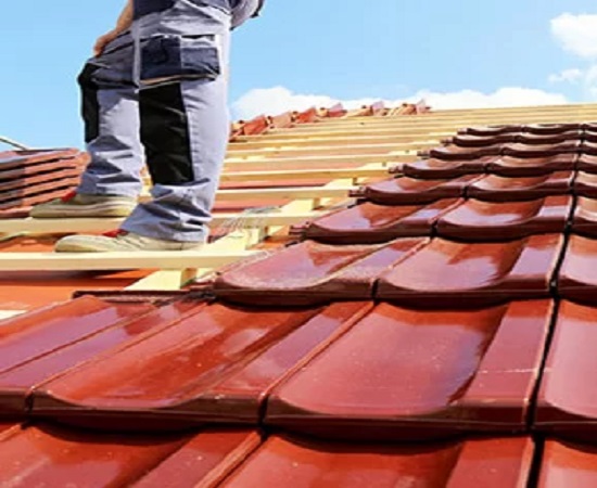 Roofer checking and coating roof tiles during routine roof maintenance in Melbourne