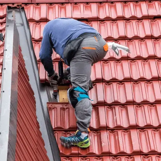 Roofer inspecting a tiled roof to decide between repairs, restoration, or re-roofing